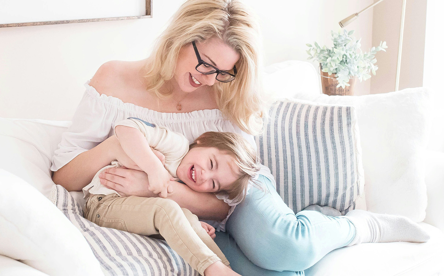 Mom that is holding a child sitting on a couch.